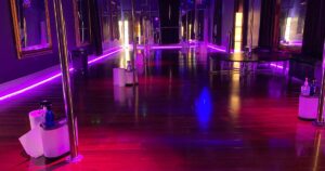 Polekittens Studio with multiple poles, mirrors, and vibrant purple lighting